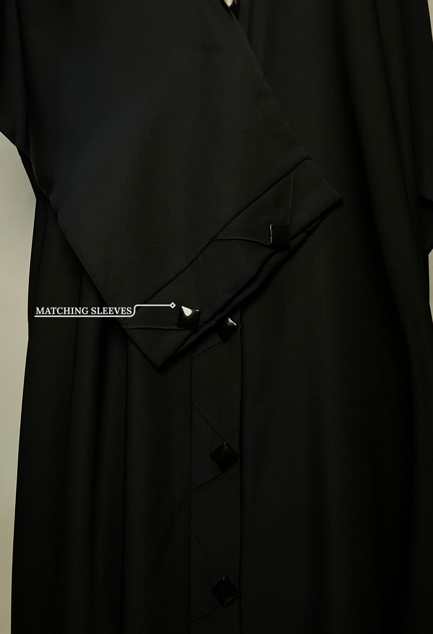 Close-up of the matching sleeve design on the Black Diamond abaya, featuring the same diamond-shaped button accents.