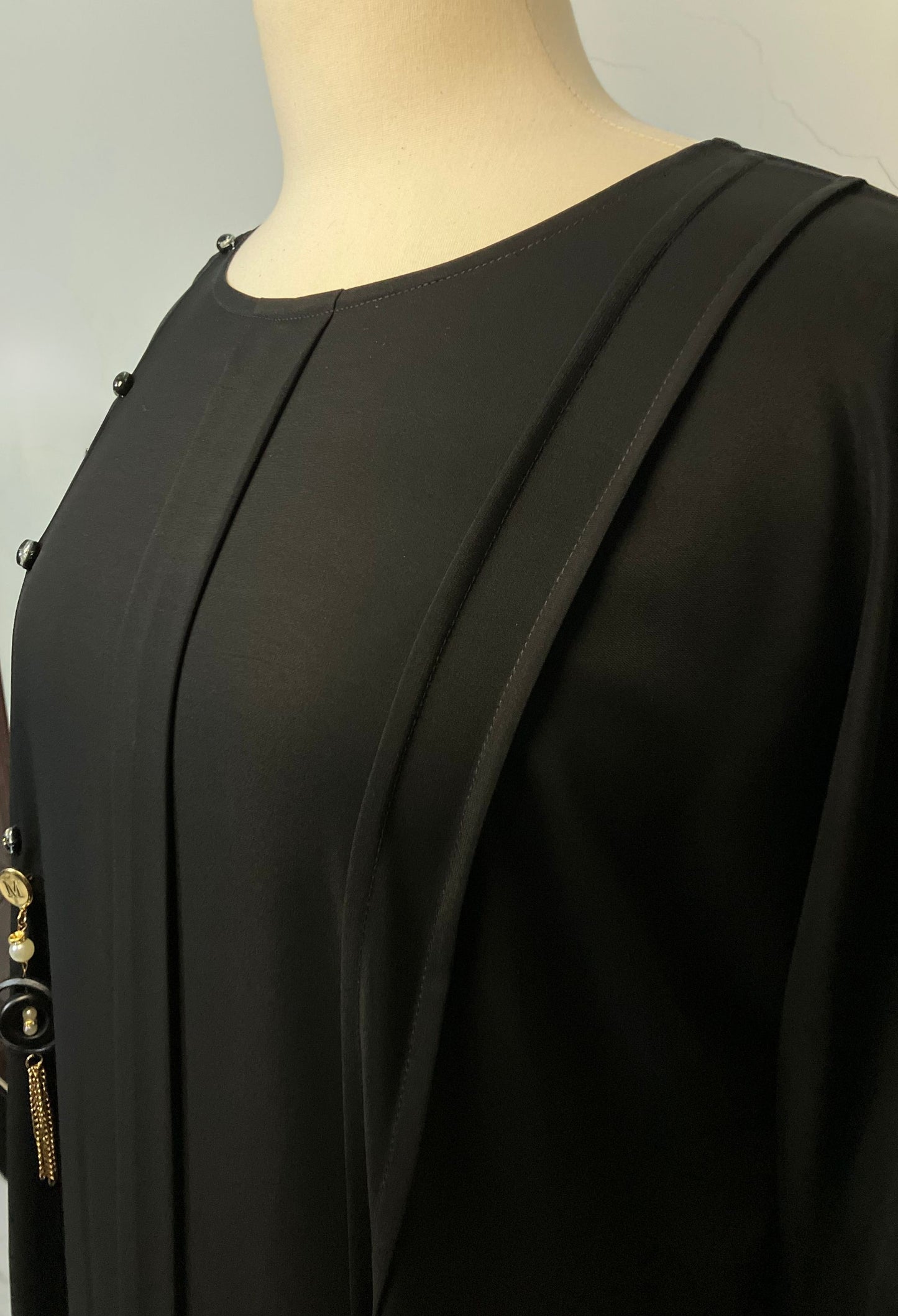Close-up detail of the elegant front pleats and decorative black buttons on the Midnight Nida abaya – Tarha.pk Classics V2.