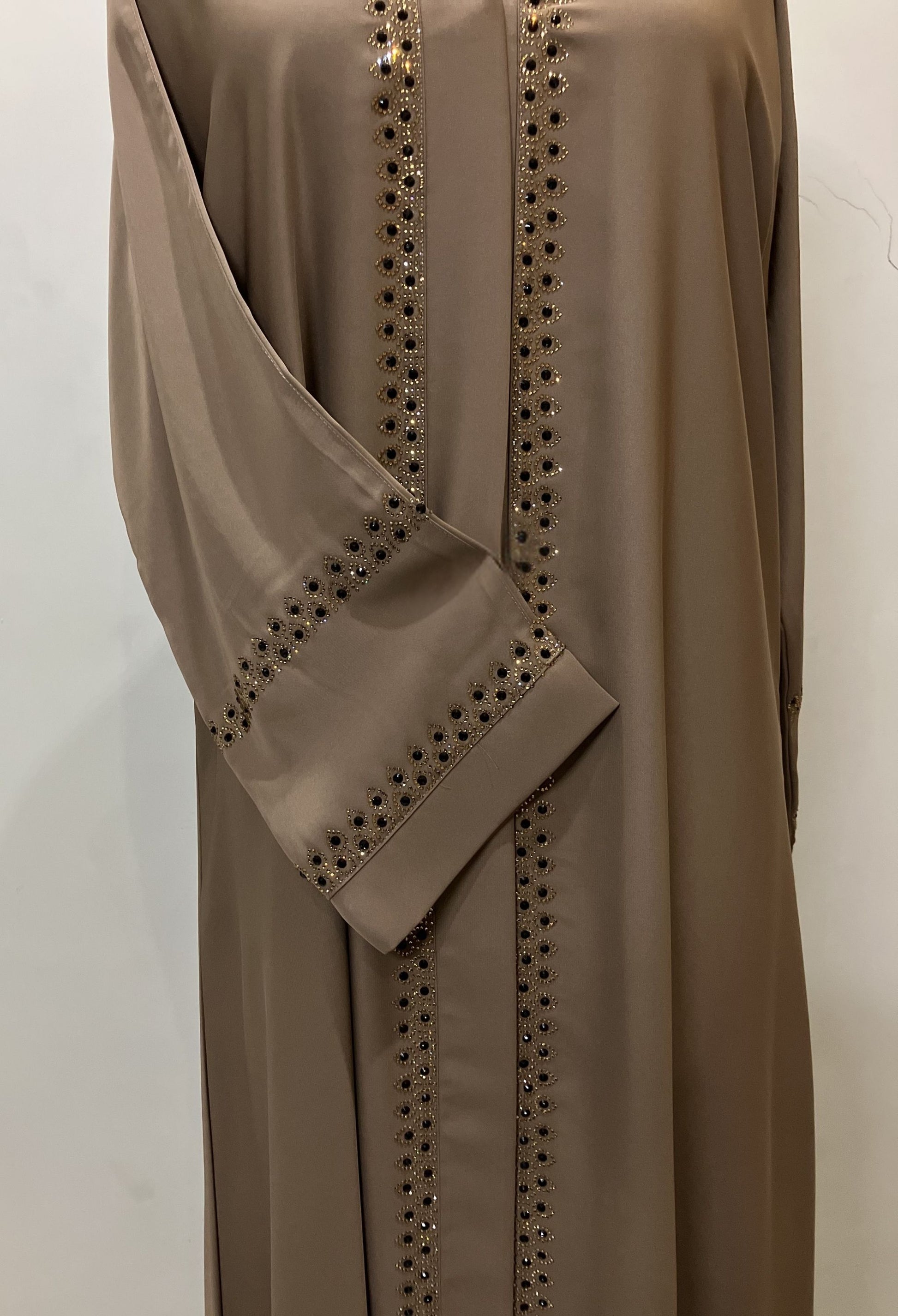 Close-up of the sophisticated golden embroidery and stitching on the sleeves of the Zahra Nida abaya.
